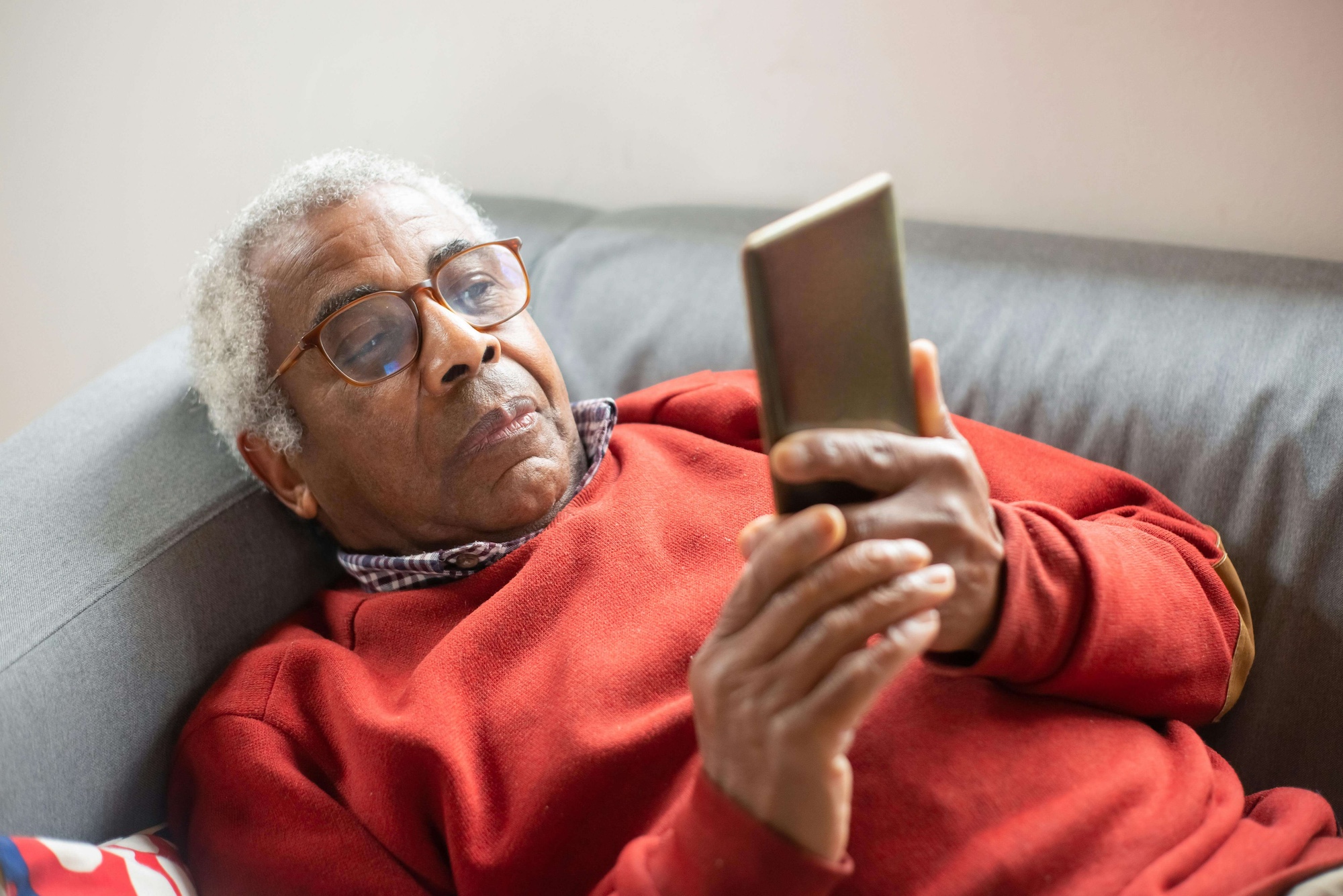 An older man using a tablet while relaxing on a sofa