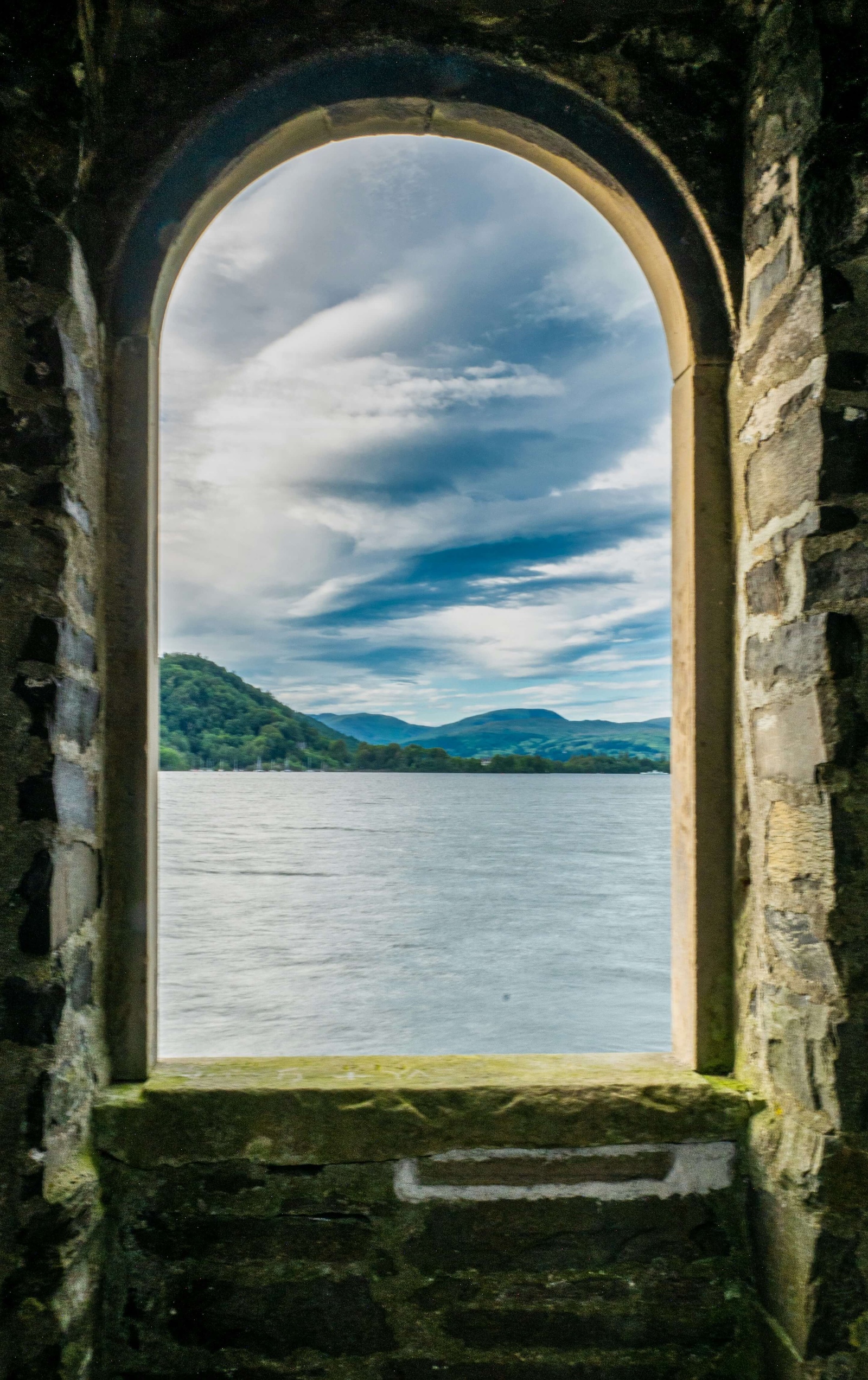 A lake and hills viewed through a stone archway
